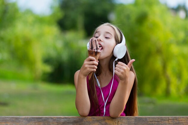 Chica con auriculares comiendo helado