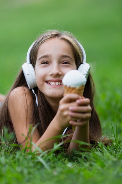 Chica con auriculares comiendo helado