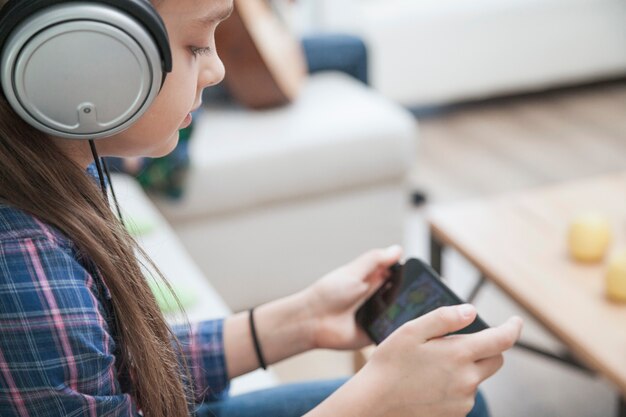 Chica en auriculares jugando juegos en smartphone