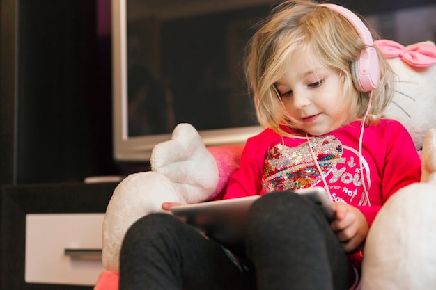 Foto gratuita chica en auriculares con tableta en sillón