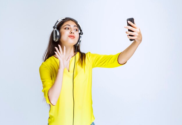 Chica con auriculares tomando su selfie o haciendo una videollamada.