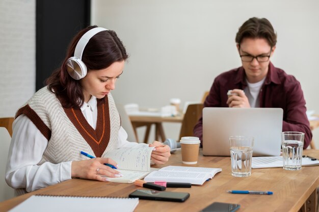 Chica con auriculares usando laptop junto a sus compañeros durante el estudio en grupo