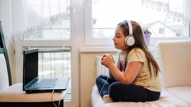 Chica en auriculares viendo la película en el sofá