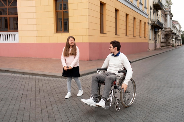 Foto gratuita chica ayudando a hombre discapacitado viajando en la ciudad