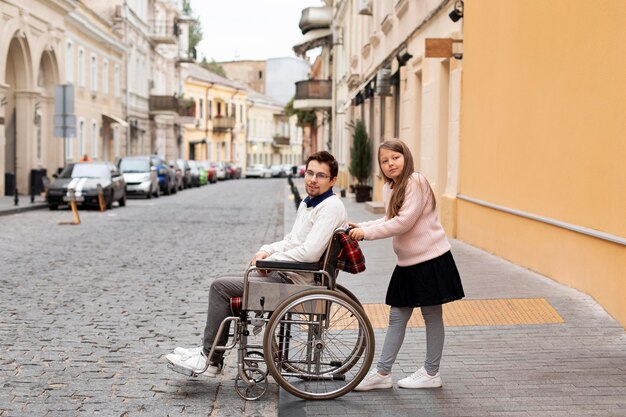 Chica ayudando a hombre discapacitado viajando en la ciudad