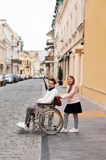 Chica ayudando a hombre discapacitado viajando en la ciudad