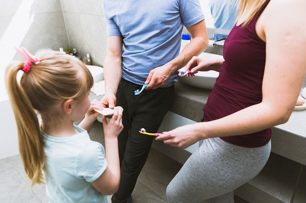 Chica ayudando a los padres con pasta de dientes