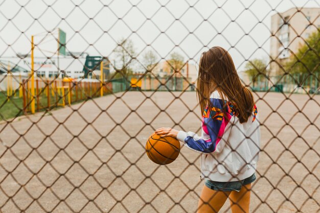 Chica con baloncesto detrás de valla