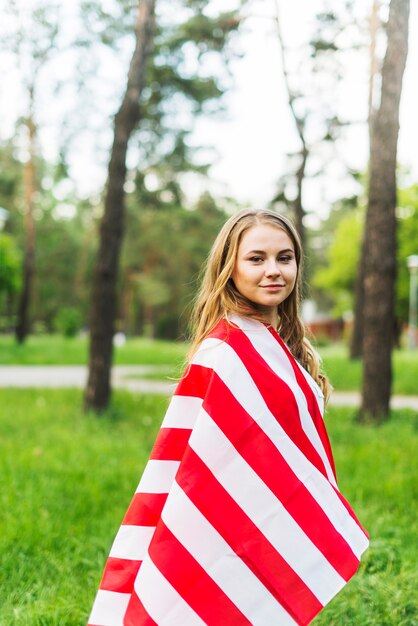 Chica con bandera americana en la naturaleza