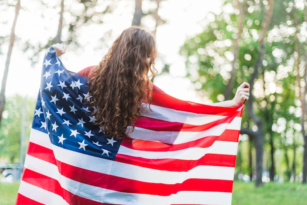 Chica con bandera americana en la naturaleza