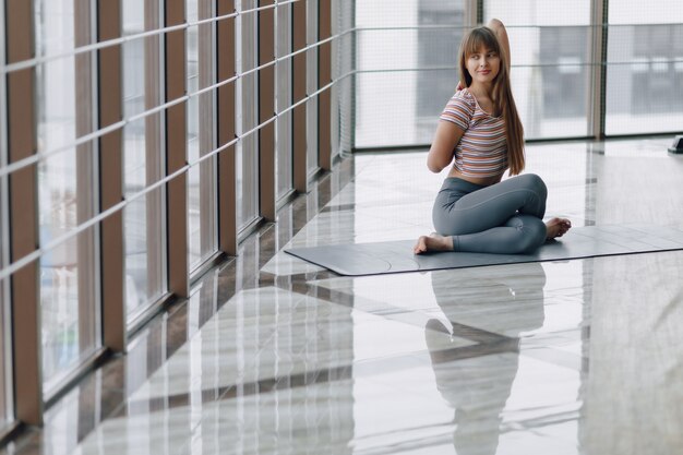 Chica bastante atractiva haciendo yoga en una habitación luminosa