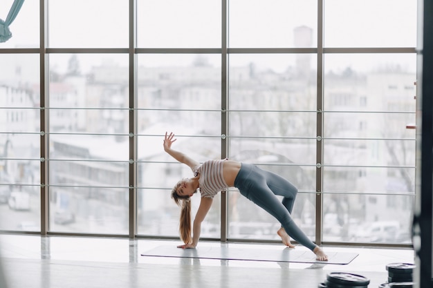 Chica bastante atractiva haciendo yoga en una habitación luminosa