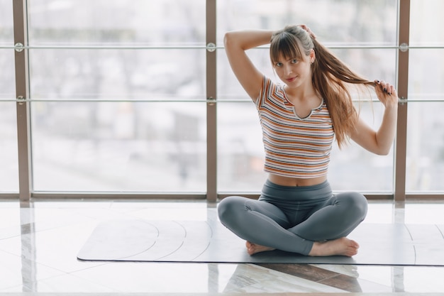 Chica bastante atractiva haciendo yoga en una habitación luminosa
