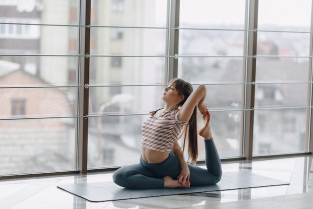 Chica bastante atractiva haciendo yoga en una habitación luminosa