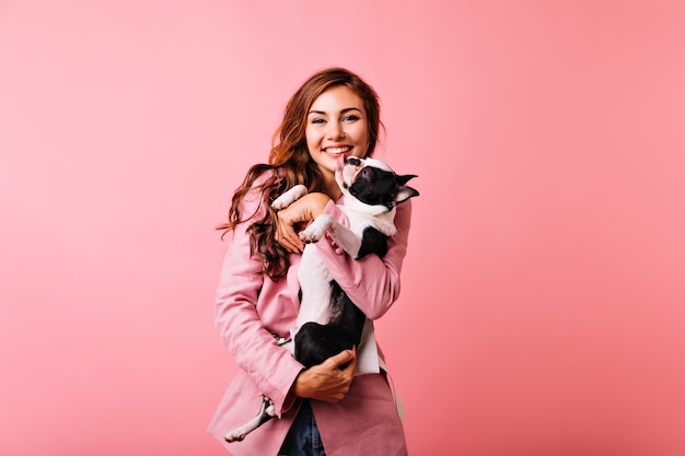 Chica bastante blanca con bulldog y riendo. Mujer caucásica alegre con perro divirtiéndose.