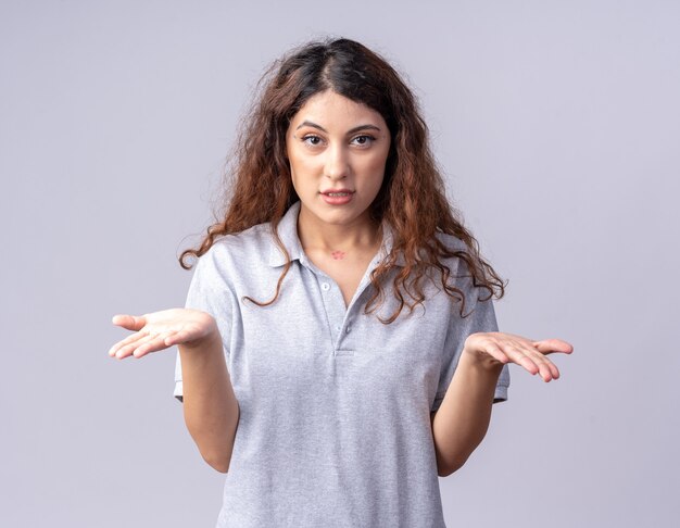 Foto gratuita chica bastante caucásica joven despistada que muestra las manos vacías aisladas en la pared blanca