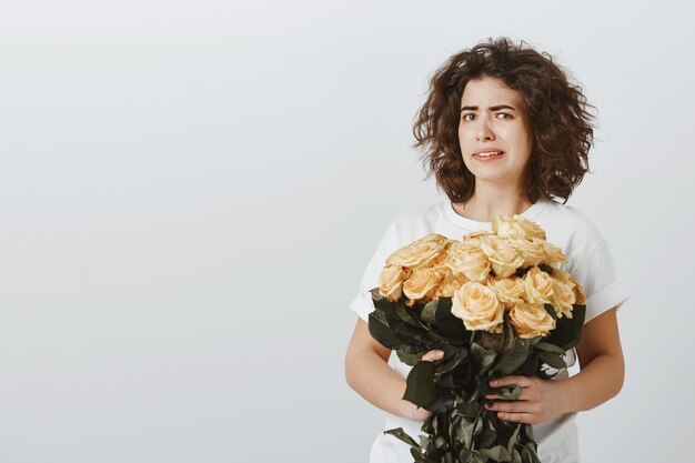 Chica bastante escéptica se encoge al mirar las flores, no le gustan las rosas, no está impresionado