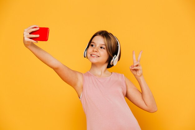 Chica bastante moderna haciendo selfie en smartphone aislado