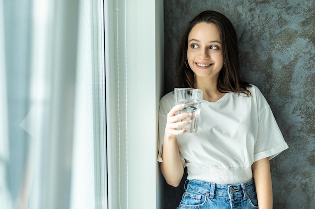 Chica bebiendo agua sentada en un sofá en casa