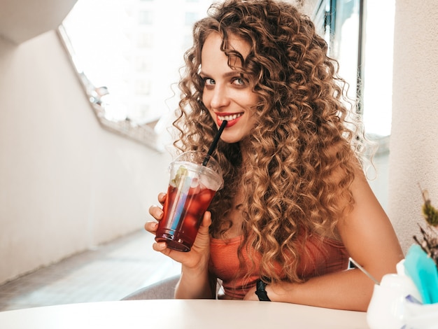 Chica bebiendo batidos frescos en vaso de plástico con paja