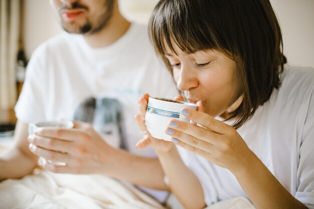 Chica bebiendo café caliente en la mañana con novio