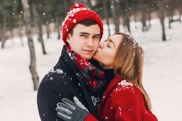 Chica besando a su novio en el parque nevado