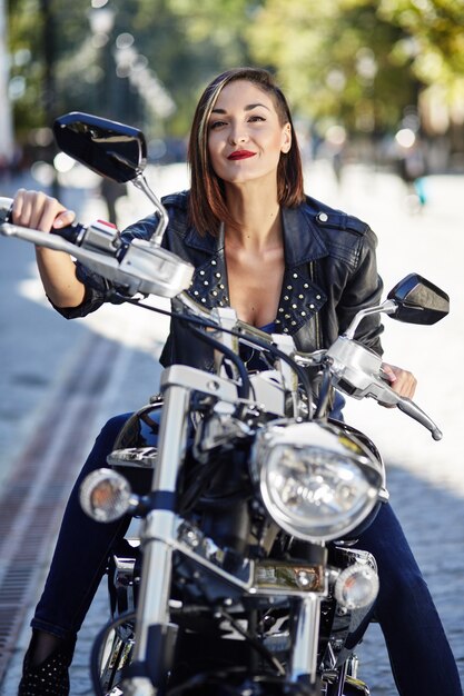 Chica biker en una chaqueta de cuero en moto