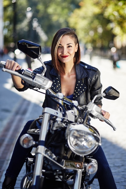 Chica biker en una chaqueta de cuero en moto