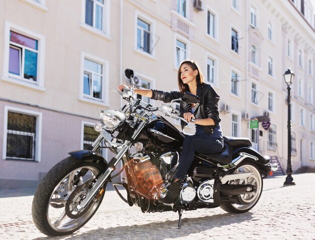 Chica biker en una chaqueta de cuero en moto