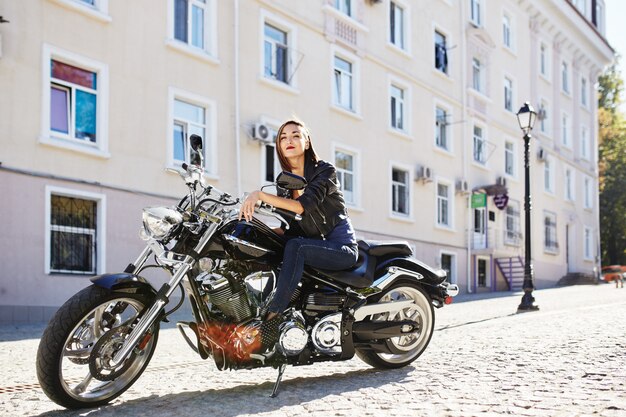 Chica biker en una chaqueta de cuero en moto