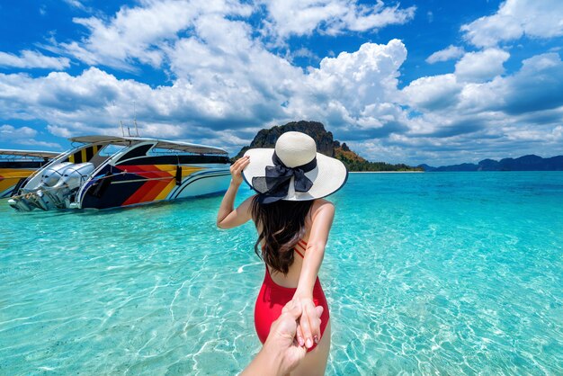 Chica bikini sosteniendo la mano del hombre y llevándolo al océano en Krabi, Tailandia