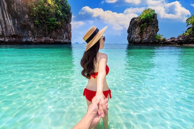 Chica bikini sujetando la mano del hombre y llevándolo a la isla de koh hong en Krabi, Tailandia