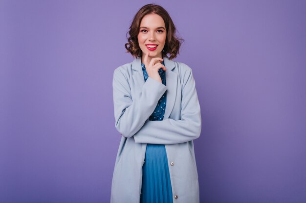 Chica blanca romántica con maquillaje de moda posando en abrigo. sonriente mujer dichosa en traje azul.