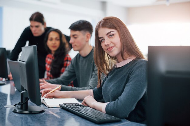 Chica bonita. Grupo de jóvenes en ropa casual que trabajan en la oficina moderna