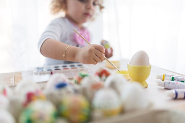 Chica borrosa tomando pintura para huevo