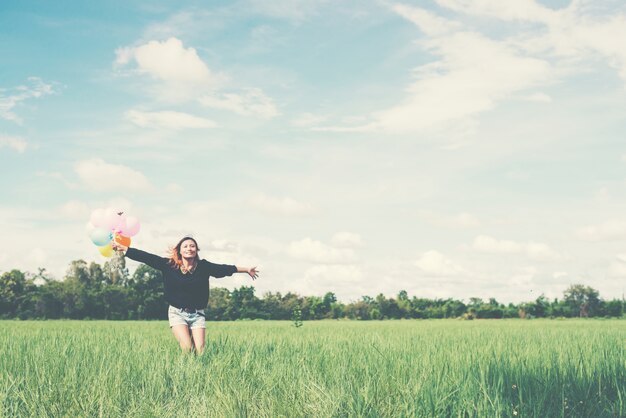 Chica con los brazos abiertos y globos