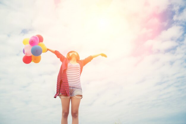 Chica con los brazos estirados y globos de colores