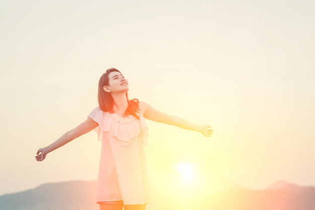 Chica con los brazos estirados y el sol detrás