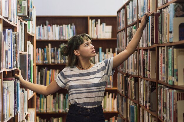 Chica buscando un libro en una estantería