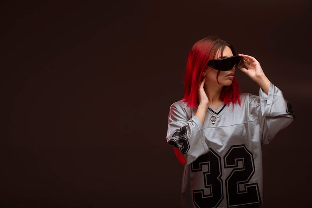 Chica de cabello rosa en estilo vanguardista con gafas de sol.