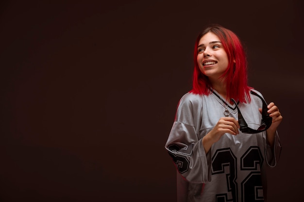 Chica de cabello rosa en estilo vanguardista sintiéndose positiva.