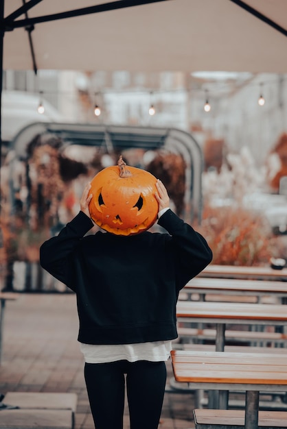 Chica con cabeza de calabaza posando en la calle