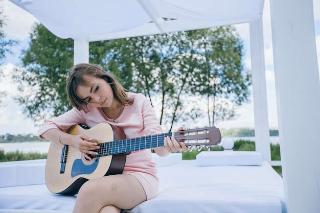 Chica con la cabeza torcida mientras toca una guitarra