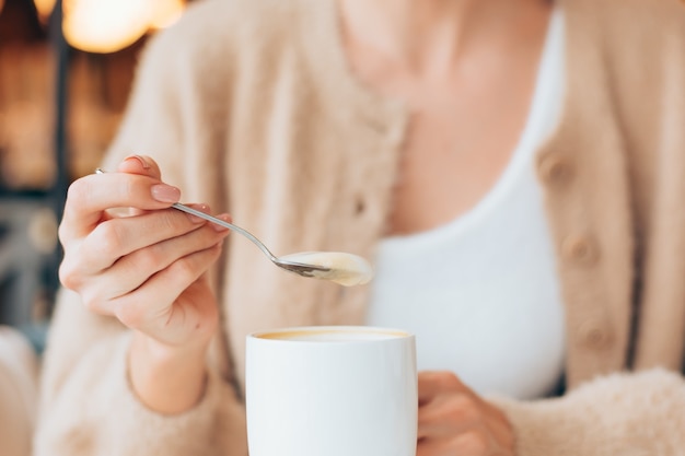 Chica en un café con una taza de café con leche caliente