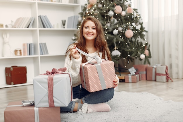 Chica con cajas de Navidad. Mujer en casa. Ladu preparándose para las vacaciones.