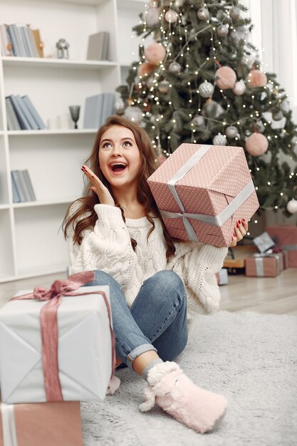 Chica con cajas de Navidad. Mujer en casa. Ladu preparándose para las vacaciones.