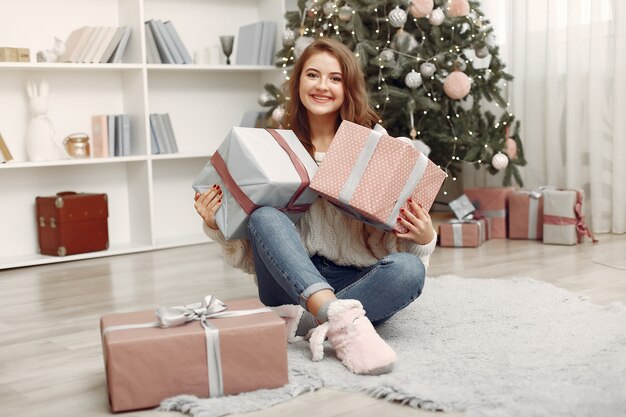 Chica con cajas de Navidad. Mujer en casa. Ladu preparándose para las vacaciones.