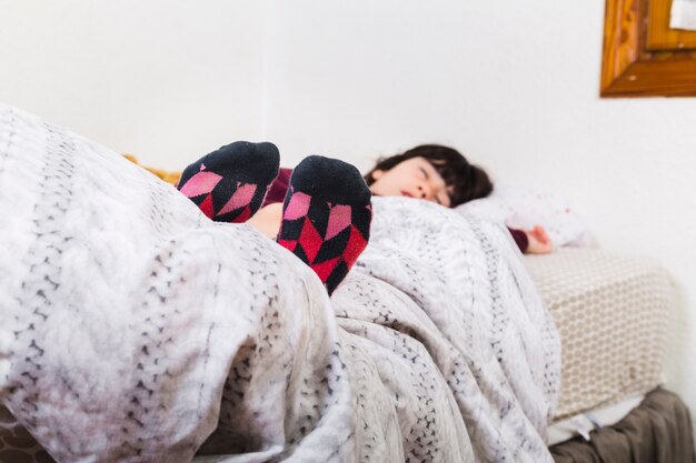 Chica con calcetines coloridos mientras duerme la siesta en la cama