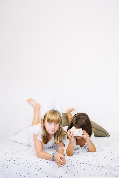 Chica con cámara y amigo en la cama