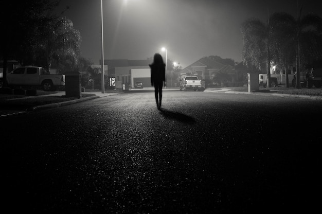 Chica caminando en una calle urbana por la noche bajo farolas